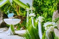 Decorated romantic wedding celebration location, table and chairs on tropical beach. Lush green foliage and white lowers Royalty Free Stock Photo