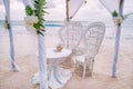 Decorated romantic wedding setting with table and chairs on sandy tropical beach with ocean and cloudy sky, Seychelles Royalty Free Stock Photo