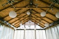 Decorated tent with bulb garland. Wedding setup white paper lanterns inside of building, under wooden roof decoration.