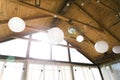 Decorated tent with bulb garland. Wedding setup white paper lanterns inside of building, under wooden roof decoration.