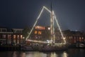 Decorated traditional sailing ship in the harbor from Harlingen in Netherlands in christmastime at night