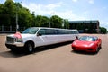 decorated wedding jeep limousine Ford excursion, stands on the road next to the red racing Ferrari in the summer. A car