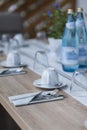 Decorated garden table set with epty coffecups and unused water glasses