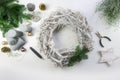 Decorating an advent wreath from white wood with green fire branches, pale golden Christmas balls and gray candles for a natural Royalty Free Stock Photo