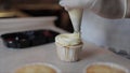 Decorating cup cake with white cream holding a pastry piping bag