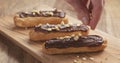 Decorating eclairs with hazelnuts on wood board Royalty Free Stock Photo