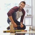 Decorating one tile at a time. Portrait of a smiling man laying floor tiles. Royalty Free Stock Photo