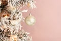 Decoration on Christmas tree - white birds and silver ball on snowy spruce on light pink background. Closeup Royalty Free Stock Photo