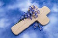 Decoration with the cross of Jesus, with blue flowers on the background with sky clouds.