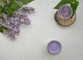 Decoration flat lay with a bouquet flowers lilac. Spa lavender candle and hydrogel balls on wooden slice on grey background Royalty Free Stock Photo