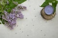 Decoration flat lay with a bouquet flowers lilac.Spa lavender candle on wooden slice on grey concrete background Royalty Free Stock Photo