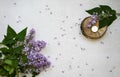 Decoration flat lay with a bouquet flowers lilac. Spa tea white candle on wooden slice on grey concrete background. Royalty Free Stock Photo