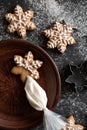 Decoration of gingerbread cookie with sugar icing. Snowflake gingersnap with unfinished ornament on plate, piping bag with glaze.