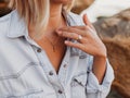 Decoration on the girl`s neck. The girl touches the chain around her neck with her hand. Close-up Royalty Free Stock Photo