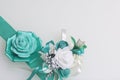 Decoration on hand in the form of a rose of emerald color, sewn to a satin ribbon. Near the wedding boutonniere. On a white backgr Royalty Free Stock Photo