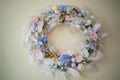 Decoration for the interior.Wreath of blue and white scale of feathers and flowers on a light wall background.