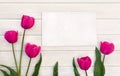 Decoration of Mothers day or Valentine day. Beautiful pink tulips and blank sheet on background of white painted wooden planks