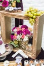 Decoration with pink, white and red flowers in golden wooden frame. Wedding decor with grapes and cookies. Fresh roses