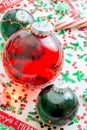 Decoration with red fluid filled Christmas ornament ball and two green filled ornament balls surrounded by a red Have Yourself A M