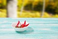 Decoration Of Red Hot Chili Pepper On Blue Wodden Board On Blurred Park Background. Set,copy Space,mock Up. Cayenne On White Plate