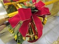 A decoration of a single golden Christmas bell ornament with bright red ribbons Royalty Free Stock Photo