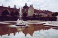 Decoration statue of a medieval fountain in the garden on the background of bright cloudy sky. Water spraying out of stature on Royalty Free Stock Photo