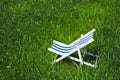 A decoration striped beach chair recliner for sunbathing and relaxing stands on a grass in a warm day, side top view