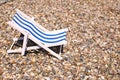 Decoration toy striped beach chair for sunbathing and relaxing stands on a stones beach in a warm sunny day