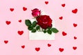 Decoration of Valentine Day. Beautiful flowers red roses in postal envelope on a pink paper background with hearts. Top view Royalty Free Stock Photo