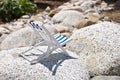 A decoration vintage striped beach chair for sunbathing and relaxing stands on a large stone on a hot sunny day, horizontal side