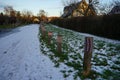 Boundary roadside poles decorated with knitted products against the background of grass under the snow in January. Berlin, Germany