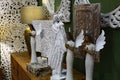 Decorative angel figures and rustical mirror frames placed on bedside bench, as displayed by company Global Interio