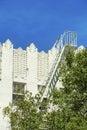 Decorative apartment building with hidden fire saftey escape ladder with front yard foliage and trees on white building