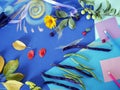 Decorative autumn composition of yellow flowers, leaves, asparagus beans, fruits, colored paper on tinted blue paper