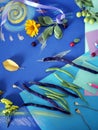 Decorative autumn composition of yellow flowers, leaves, asparagus beans, fruits, colored paper on tinted blue paper