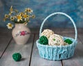 Decorative basket with straw balls and a small bouquet of wild daisies in a porcelain vase
