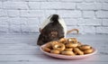 Decorative black and white cute rat sniffs and eats round bagels from a pink ceramic plate. Rodent close-up on a background of