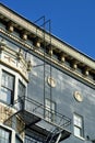 Decorative blue brick building with fire escape ladder metal as a detail shot with white facade and windows in afternoon Royalty Free Stock Photo