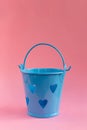 Decorative blue bucket with heart shaped holes on pink background. Festive concept Royalty Free Stock Photo