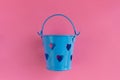 Decorative blue bucket with heart shaped holes on pink background. Festive concept Royalty Free Stock Photo