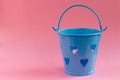 Decorative blue bucket with heart shaped holes on pink background. Festive concept Royalty Free Stock Photo