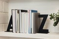 Decorative bookends with books and houseplant on shelf indoors