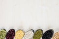 Decorative border of assortment pulses beans in spoons with copy space on white wood background. Royalty Free Stock Photo
