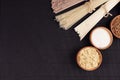 Decorative border of bundles raw noodles with ingredient in wooden bowls on black striped mat background with copy space, top view Royalty Free Stock Photo