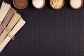 Decorative border of bundles raw noodles with ingredient in wooden bowls on black striped mat background with copy space, top view Royalty Free Stock Photo