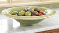 A decorative bowl filled with various fruits on a countertop Royalty Free Stock Photo