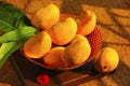 A decorative bowl full with fresh Alphonso mangoes, mango leaves, top view