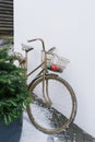 A decorative bronze Bicycle with a basket containing Christmas balls stands near the Christmas tree on the winter street near the