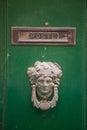 Decorative bronze traditional malttese door handle in the form of a beautiful woman`s head on a green painted door Royalty Free Stock Photo