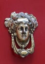 Decorative bronze traditional malttese door handle in the form of a beautiful woman`s head on a red painted door. Malta Royalty Free Stock Photo